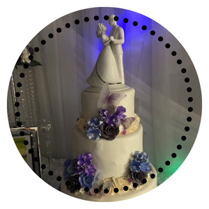 white wedding cake with purple butterflies and flowers. White bride and groom wedding topper on top.